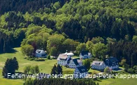 Eine Luftaufnahme einer kleinen Ansammlung von Häusern umgeben von Wäldern.