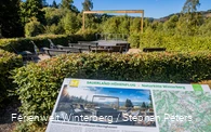 Informationstafel zum Naturkino mit Blick auf die hölzernen Liegebänke und den Landschaftsrahmen.