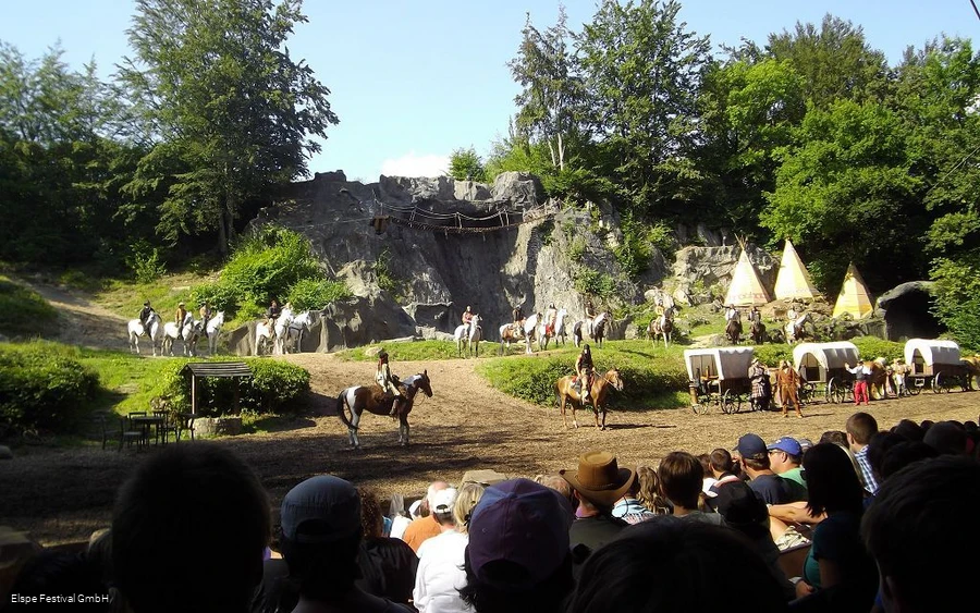 Elspe-Festival Der Blick des Publikums ist Richtung Bühne des Eslpe-Festivals gerichtet, wo Reiter, Pferde, Cowboys und Indianer zu sehen sind.