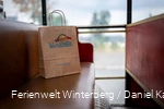 Eine Winterberger Einkaufstüte aus Papier auf einer roten Sitzbank.