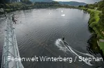Ein Wasserskifahrer wird an einem Seil über den See gezogen.