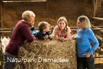 Familie mit Kindern auf einem Strohballen Familienbauernhof Fass