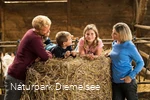 Familie mit Kindern auf einem Strohballen Familienbauernhof Fass