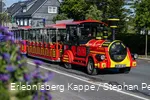 Eine rot-gelbe Eisenbahn fährt die Straße entlang.