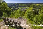 Ein Aussichtspunkt mit einer Bank mit Weitblick auf Wiesen und Wälder.
