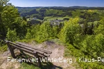 Ein Aussichtspunkt mit einer Bank mit Weitblick auf Wiesen und Wälder.